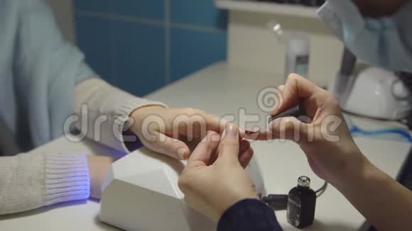 美容院年轻女性指甲涂胶清漆的特写视频的预览图