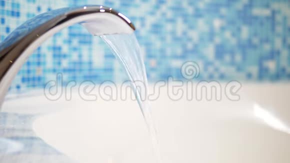 特写水从一个豪华的水龙头流到一个巨大的现代浴缸靠着蓝色的马赛克墙视频的预览图