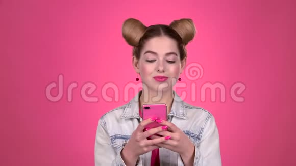 一个粉红色话题的青少年在电话上打印一条信息粉色背景慢动作视频的预览图