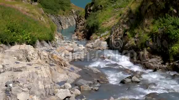一条冰川融化的河流流过岩石流入位于瑞士高山峰上的一个湖泊视频的预览图