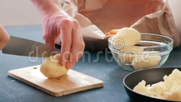 特写男人他的手在木板上切一个土豆然后把它放在一个油炸锅上视频的预览图