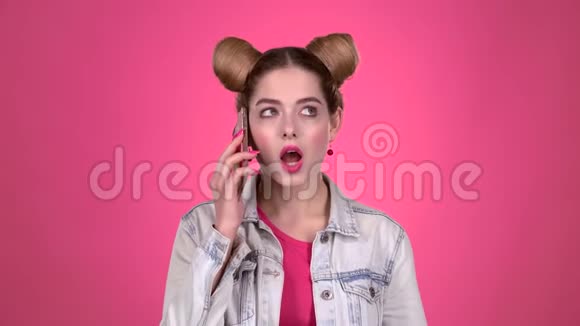 青少年和她的兄弟姐妹在电话里说话粉色背景慢动作视频的预览图
