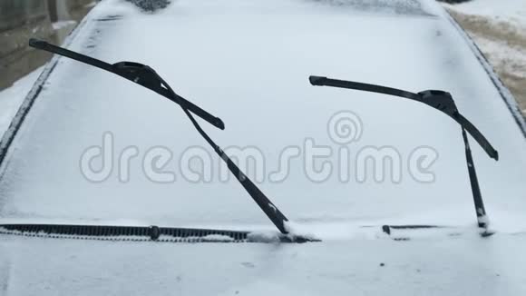 把车停在前面挡风玻璃雨刷在冬天远离被雪覆盖的窗户视频的预览图