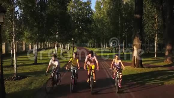 四个运动的朋友在公园里骑自行车视频的预览图