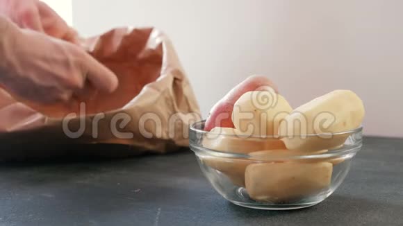 一碗土豆削皮土豆男人的手清理土豆在一个生态袋的背景视频的预览图