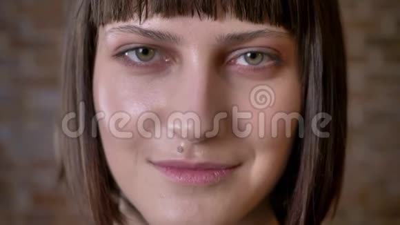 年轻开朗的女人留着短发看着相机微笑着被孤立在砖背景上的肖像视频的预览图