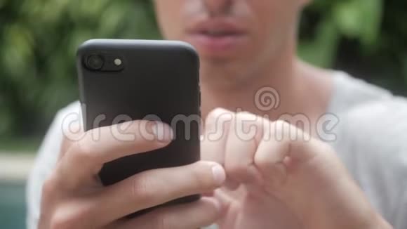 关闭男子使用智能手机户外有平板电脑的年轻人在社交网络上花园里的一个男人视频的预览图