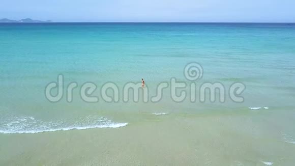 鸟瞰女子在碧海中游泳在蓝色天际线背景下的绿松石海中的无人机观看女人视频的预览图