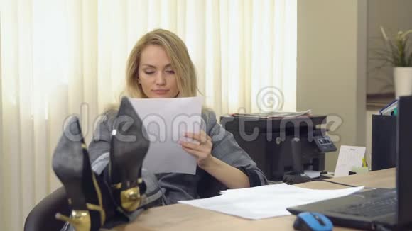 年轻的商务女性在笔记本电脑前的现代办公桌前打哈欠视频的预览图