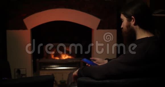 一个长胡子的男人在壁炉附近的智能手机上说话视频的预览图