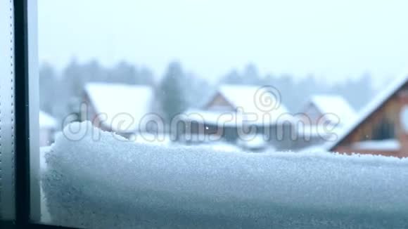 从积雪覆盖的窗户上看到村庄的房屋和森林视频的预览图