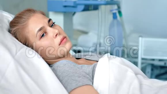 躺在医院房间里的年轻女性病人伤心难过的女人在现代诊所里思考生活视频的预览图