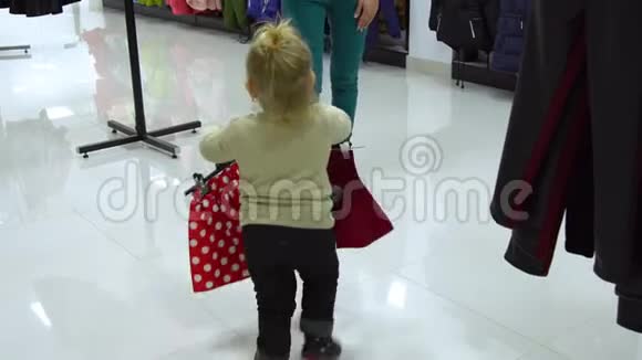 一个可爱的小女孩和她的母亲在一家精品店里家精品店妈妈和孩子在商店里挑选衣服视频的预览图