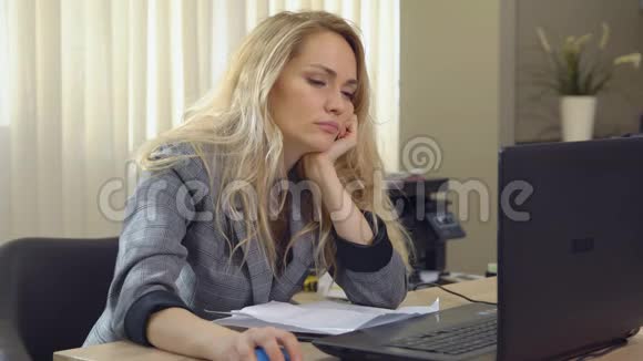 女商人下班后在笔记本电脑键盘上打盹视频的预览图