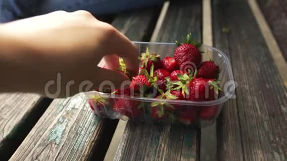 两个人从盒子里拿出一个成熟多汁的欧格拉尼克草莓健康零食概念视频的预览图