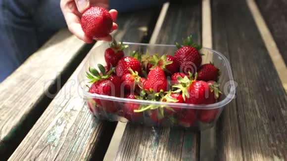 白种女人的手从一盒新鲜成熟的水果中取出一个草莓视频的预览图