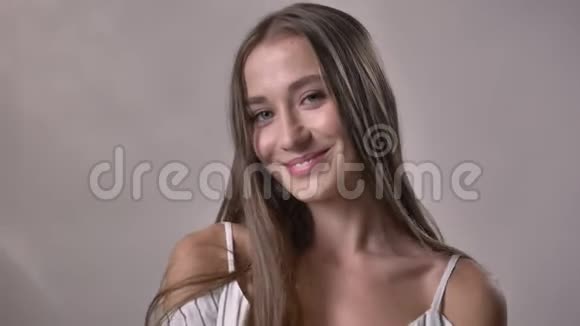 年轻女孩正在镜头前观看移动微笑调情的概念灰色背景视频的预览图