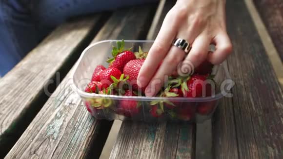 一个女人正在吃一个多汁的成熟草莓一只采浆果的雌性手的特写视频的预览图