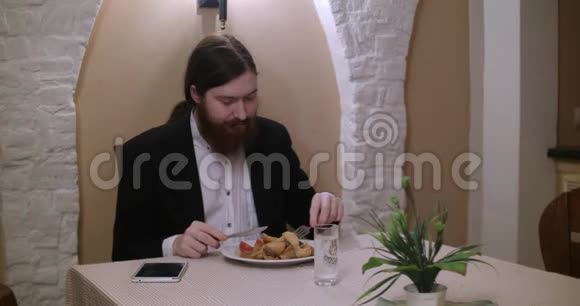 一个留胡子的年轻人在餐馆吃饭用平板电脑视频的预览图