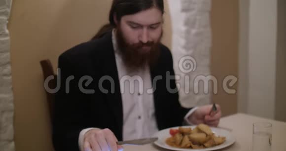 一个留胡子的年轻人在餐馆吃饭用平板电脑视频的预览图