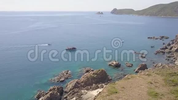 帆船在蓝色海水和岩石悬崖鸟瞰无人驾驶帆船在海湾和山崖上航行视频的预览图
