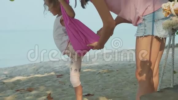 妈妈教她的孩子在海滩上用吊床做瑜伽练习视频的预览图