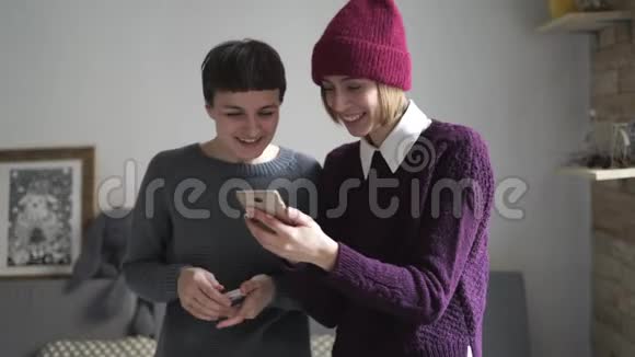 两个女人在房间里用手机笑女人八卦数字生活方式视频的预览图