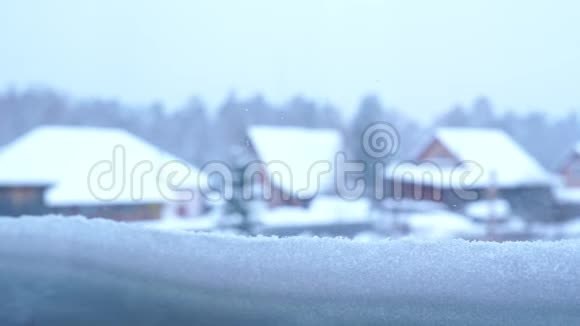 从积雪覆盖的窗户上看到村庄的房屋和森林视频的预览图