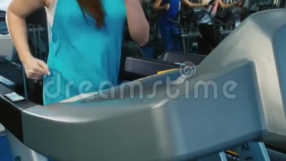 在健身房训练的漂亮女人在跑步机上跑步视频的预览图