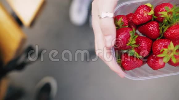 女人在阳光明媚的日子里展示她的有机草莓上景视频的预览图