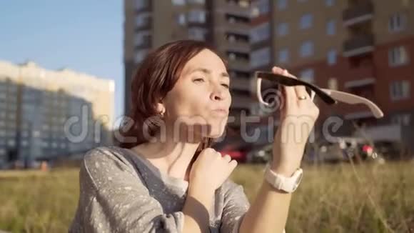 城市里戴太阳镜的漂亮年轻女人女人调整她的头发看着太阳镜的倒影视频的预览图