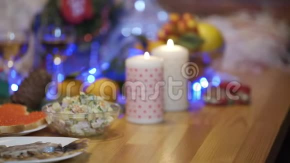 在蜡烛和圣诞树的背景下双手放在节日桌上的火腿卷上视频的预览图