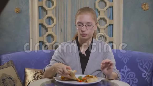戴眼镜的年轻女孩在一家东方餐馆吃肉饼视频的预览图
