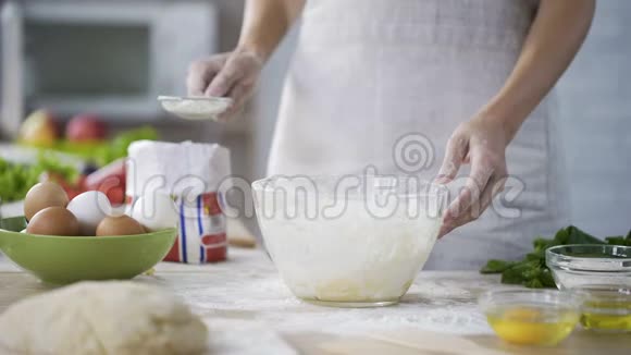 女人用手把面粉用面团筛在玻璃碗上面包店视频的预览图