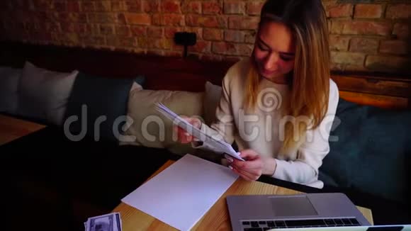 在咖啡馆里用纸和笔记本电脑工作的女性文案视频的预览图