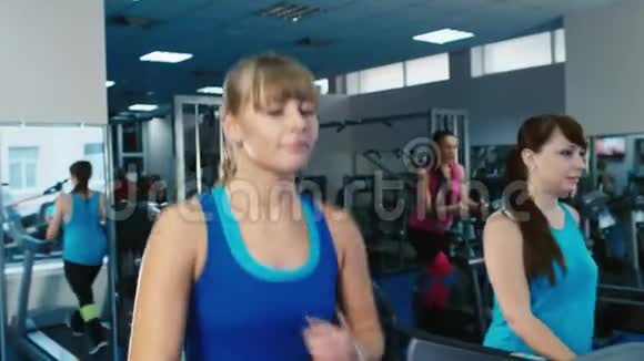 两个迷人的女孩在健身房的跑步机上锻炼视频的预览图