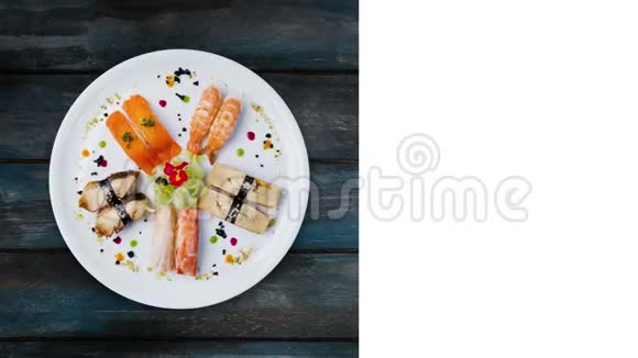 日本菜旋转生鱼片设置在白色圆板上装饰有小花俯视木制背景视频的预览图