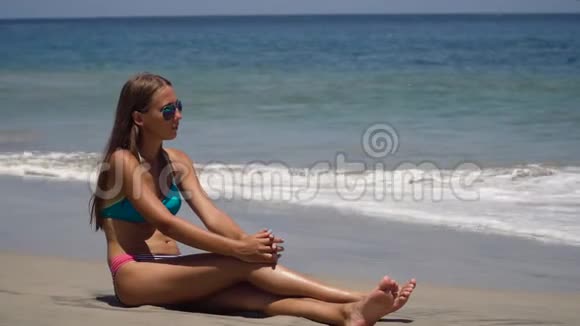 戴着太阳镜的女孩坐在海滩上视频的预览图