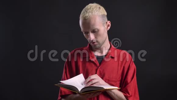 金发男人在看书在摄像机前看着黑色背景视频的预览图