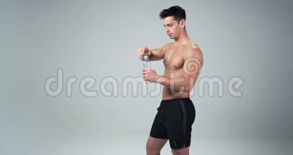 一个年轻的帅哥肌肉男喝水隔离在白色背景上视频的预览图