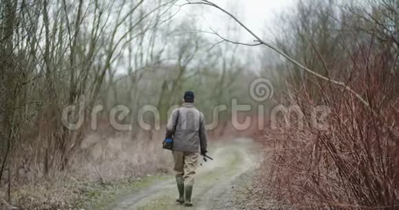 一个人拿着鱼竿在光秃秃的树间行走视频的预览图