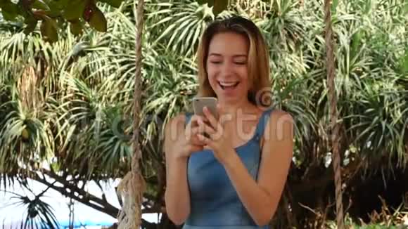 慢动作模特女孩使用互联网智能手机放松花园视频的预览图