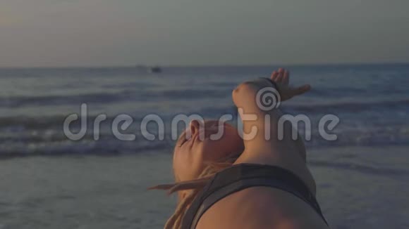 日落时瑜伽练习的特写勇女在沙滩上做瑜伽运动视频的预览图