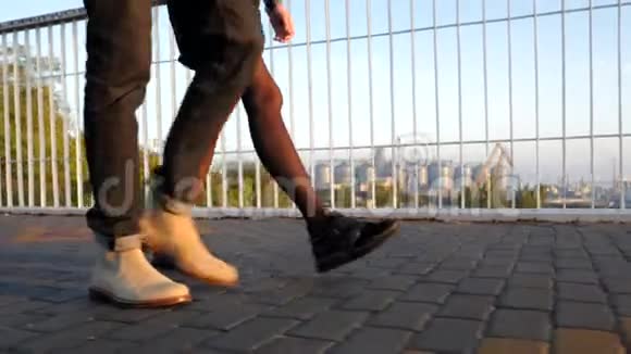 夏天在桥上行走的一对无法辨认的年轻夫妇的腿日落的光商业中的时尚快乐伴侣视频的预览图