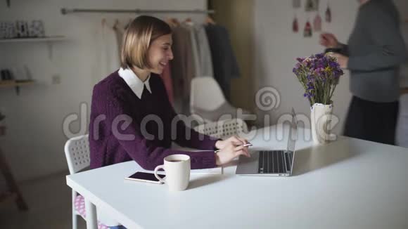 年轻女子坐在桌子旁在笔记本键盘上打字朋友笔记本电脑视频的预览图