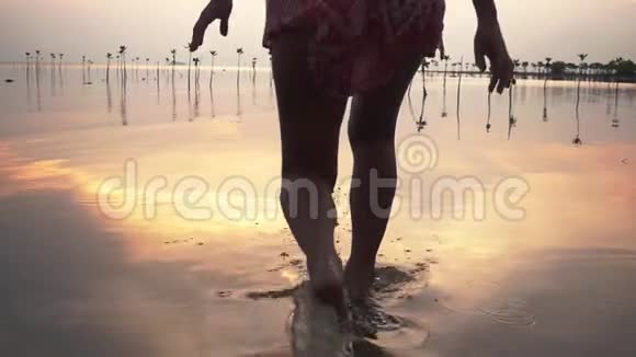 在美丽的夕阳下穿着短裙的年轻女子在海滩上奔跑慢动作1920x1080视频的预览图