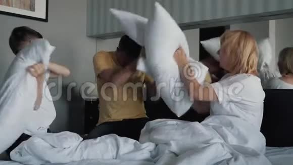一个幸福微笑的家庭在床上枕头在床上玩白色床单幸福家庭的概念视频的预览图