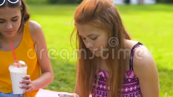 在公园里玩智能手机和奶昔的少女视频的预览图