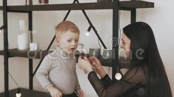 年轻的母亲和小儿子从家里的杯子里喝水视频的预览图