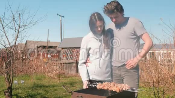 两个男人和女人在后院的木炭烤架上做什什利克肉一起聊天和微笑视频的预览图